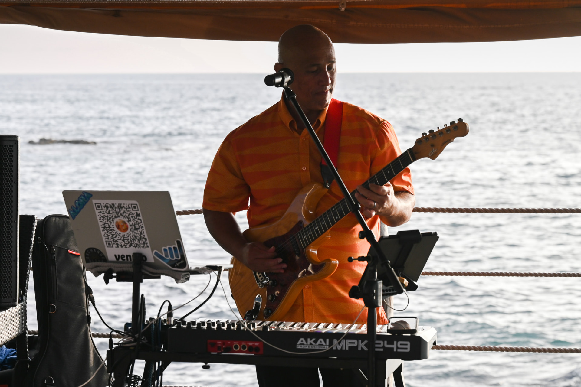Local musician playing guitar beside the ocean at Huggo's On the Rocks
